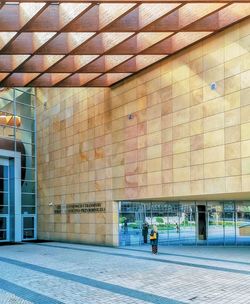 Man walking on footpath against building in city