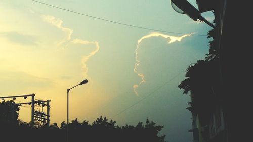 Low angle view of power lines against cloudy sky