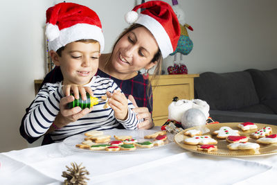 Cute boy preparing gingerbread cookies with mother at home