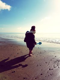 Rear view of woman on beach against sky