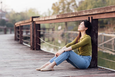 Portrait of young woman sitting on railing