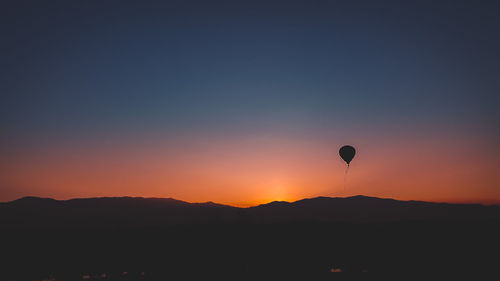 Silhouette hot air balloon against clear sky during sunset