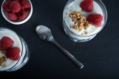 Two glass bowls of vanilla yogurt with cinnamon roll granola and raspberry topping
