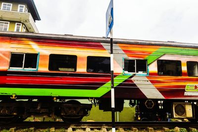 Multi colored flags on train against sky