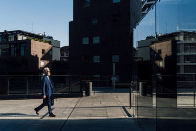 Senior businessman walking outside office building on sunny day