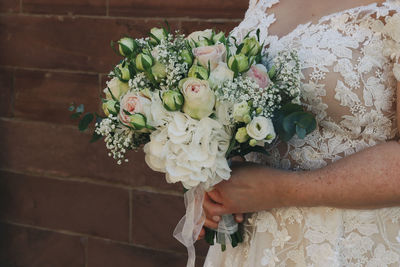 Midsection of bride holding bouquet