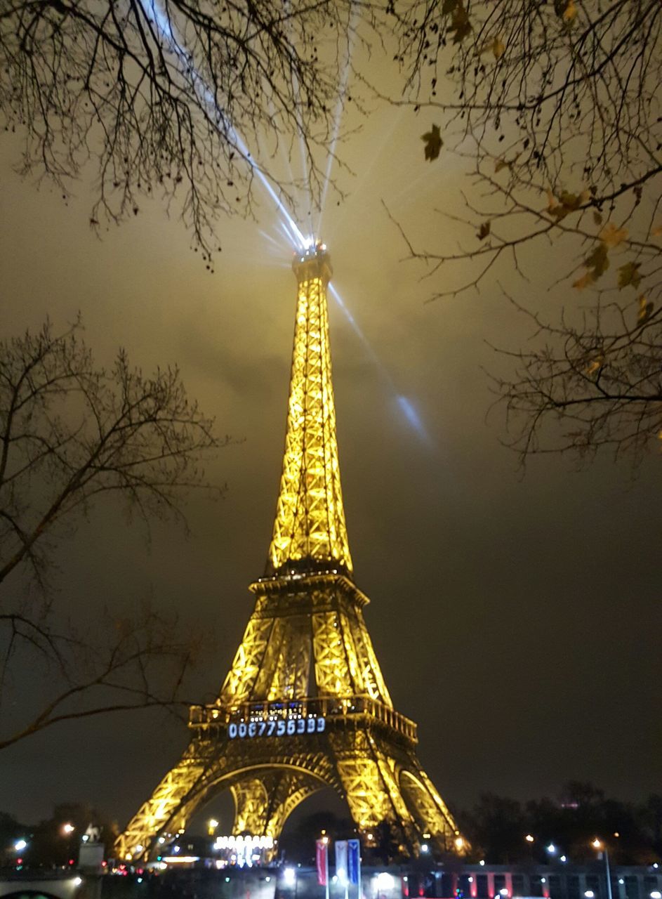 architecture, built structure, low angle view, illuminated, travel destinations, famous place, eiffel tower, international landmark, tourism, tree, night, capital cities, travel, sky, tower, building exterior, tall - high, city, culture, bare tree
