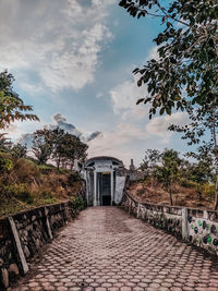 Footpath leading to building against sky