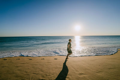 Woman standing on beach against clear sky