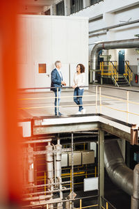 Male and female colleagues having discussion while standing in industry