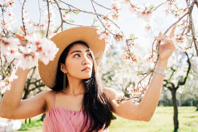 Portrait of beautiful young woman standing by flowering tree