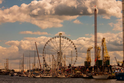 Ferris wheel at harbor against sky in city