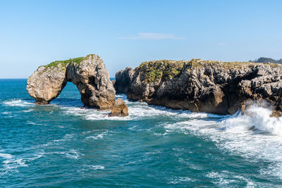 Rocks in sea against blue sky