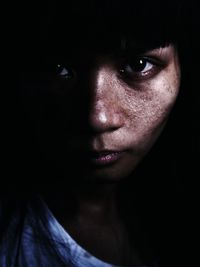 Close-up portrait of serious young woman in dark