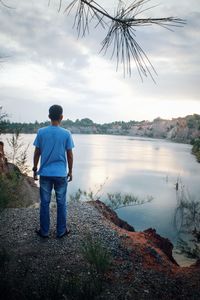 Man standing on hill against lake