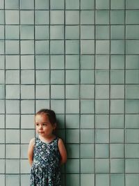 Portrait of cute girl standing against wall