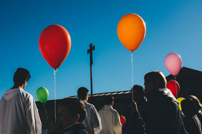 Low angle view of people against blue sky