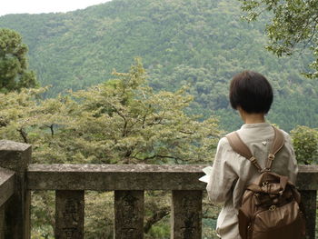 Rear view of woman standing by railing on mountain