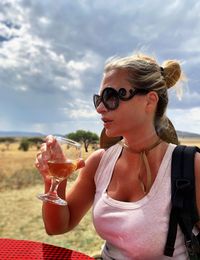 Woman having drink while sitting on table against sky