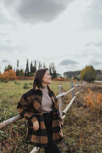 Young woman standing on field against sky