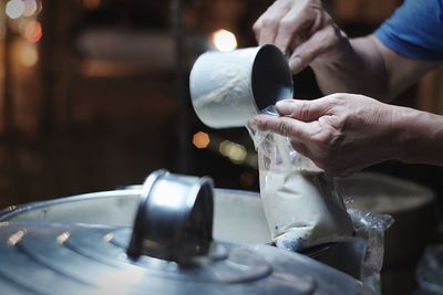 Cropped image of person pouring soy milk in plastic