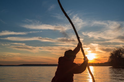 Silhouette man on beach against sky during sunset