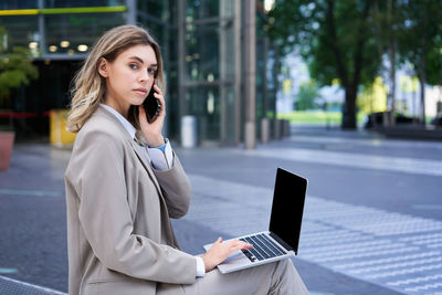 Young businesswoman using laptop while sitting at office