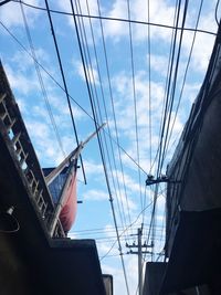 Low angle view of electricity pylon against cloudy sky