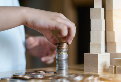 Close-up of hand holding glass of coins on table