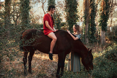 Full length of woman sitting on field in forest