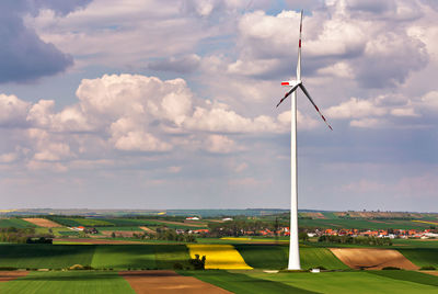 Windmill on field against cloudy sky