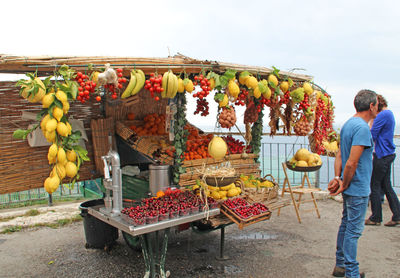 Vendor standing against concession stand selling fruits on roadside