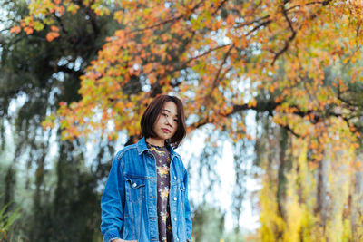 Portrait of mid adult woman standing against autumn trees