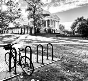 Bicycle parked by building in city against sky