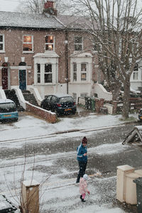 Full length of woman in snow against buildings in city