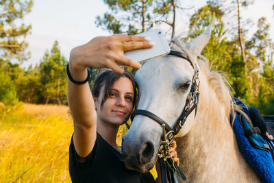 Young woman taking selfie with horse