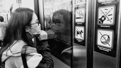 Rear view of woman looking through glass window