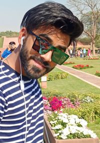 Portrait of young man wearing sunglasses while standing against trees