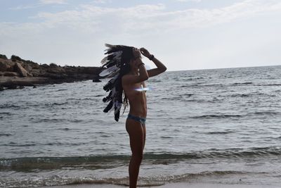 Woman standing on beach against sky