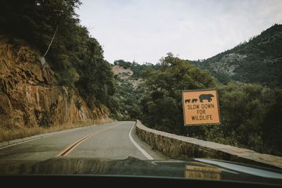 Road sign against sky seen through car windshield