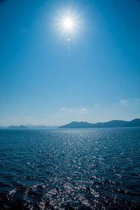 Scenic view of sea against blue sky on sunny day