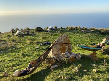 Panoramic view of people relaxing on land against sky