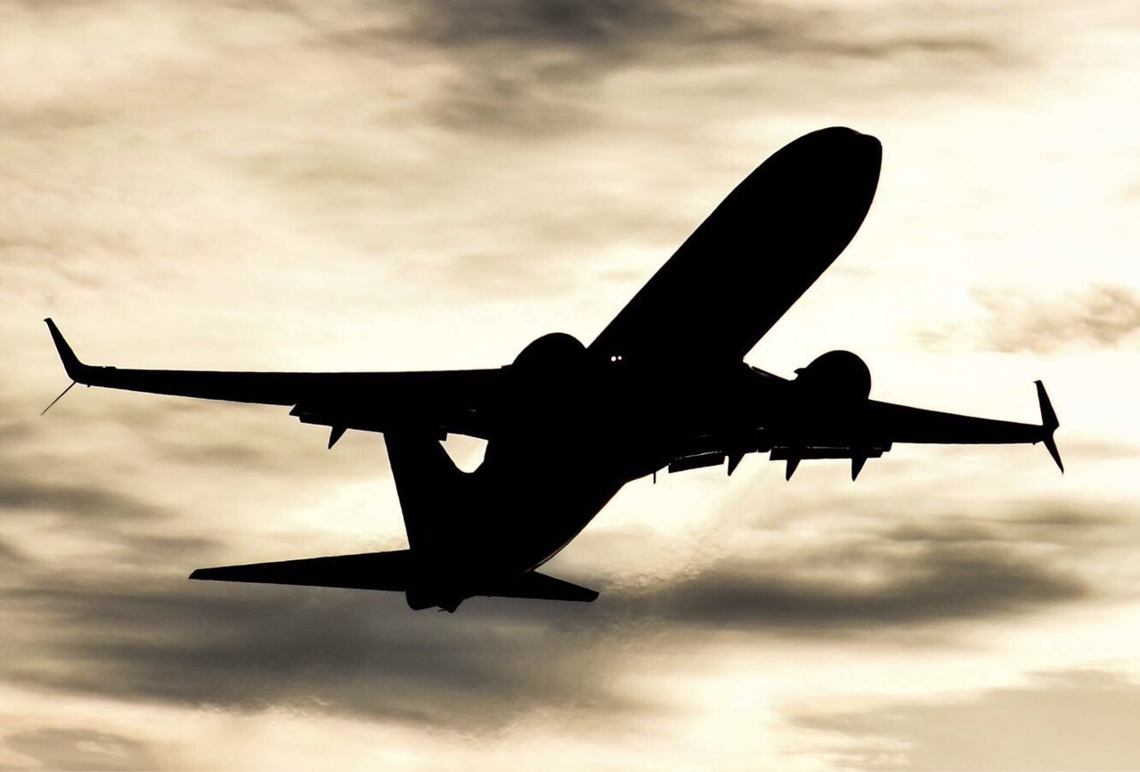 LOW ANGLE VIEW OF SILHOUETTE AIRPLANE AGAINST SKY AT SUNSET