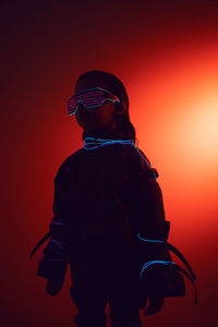 Portrait of a robot boy child from the future in neon glasses and jacket at night