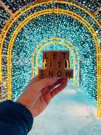 Cropped hand of man holding illuminated street at night