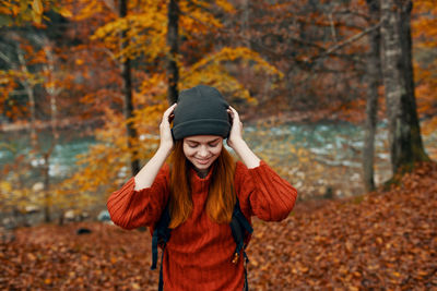 Full length of young woman standing in park during autumn
