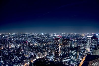 Illuminated cityscape against sky at night