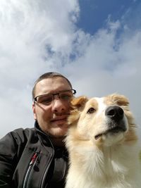 Low angle portrait of man with dog against sky