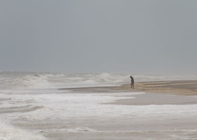 Man on beach against clear sky