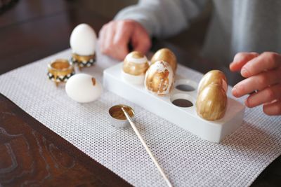 Midsection of man painting eggs at table